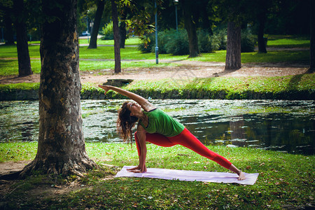 年轻女子在pon旁的公园户外练习瑜伽图片