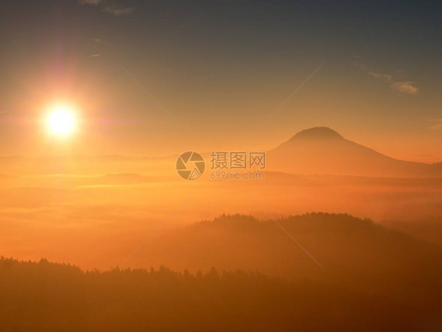 红色滤镜照片红色黎明朦胧的黎明在美丽的小山峰从有雾的背景中伸出图片