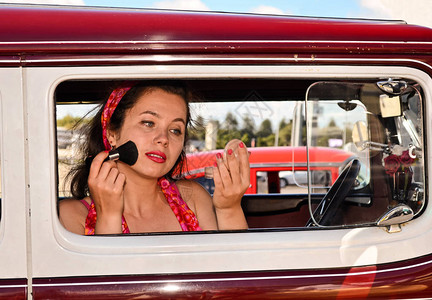 年轻女子在古老的汽车和时装秀上图片
