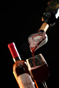 在深色背景下将红酒倒入醒酒器图片