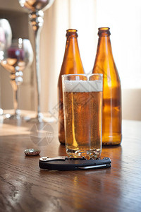 两个空的棕色玻璃啤酒瓶一杯啤酒瓶盖和一个开瓶器图片