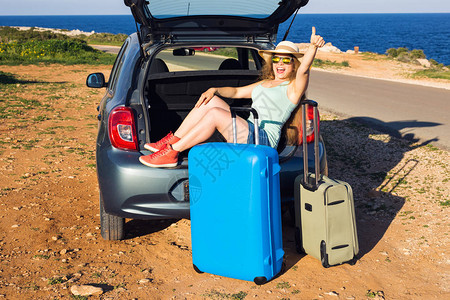 旅行暑假和期概念带着手提箱的年轻女子在汽车旅行她坐在车后图片