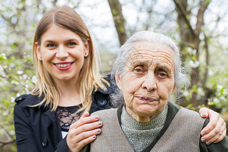 公园中一名年老生病妇女及其年轻照顾者图片