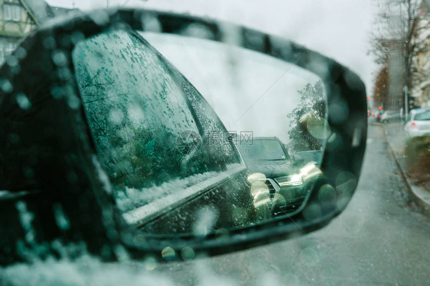 在雪天的后视镜中查看hrou汽车窗口由驱动器点ov通过湿挡风玻璃窗口图片