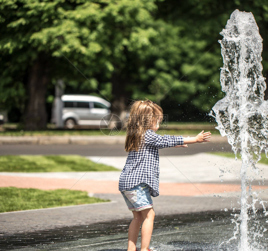 小女孩在喷泉里玩耍暑图片