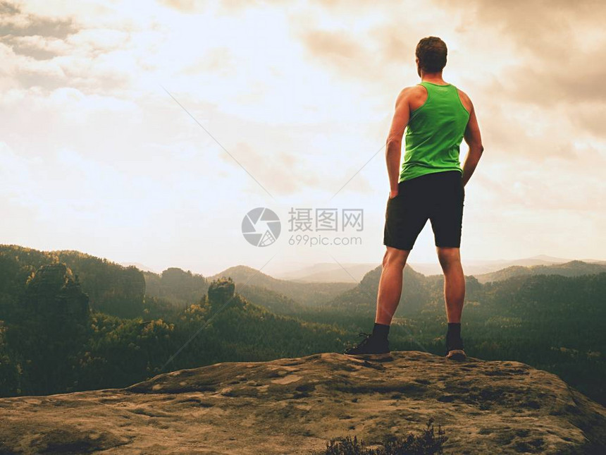 高个子在山边的山顶上享受自由单独的游客看着迷雾笼罩的山谷到太阳大自然中的美好时刻穿着黑色裤子和T恤的短发男子图片