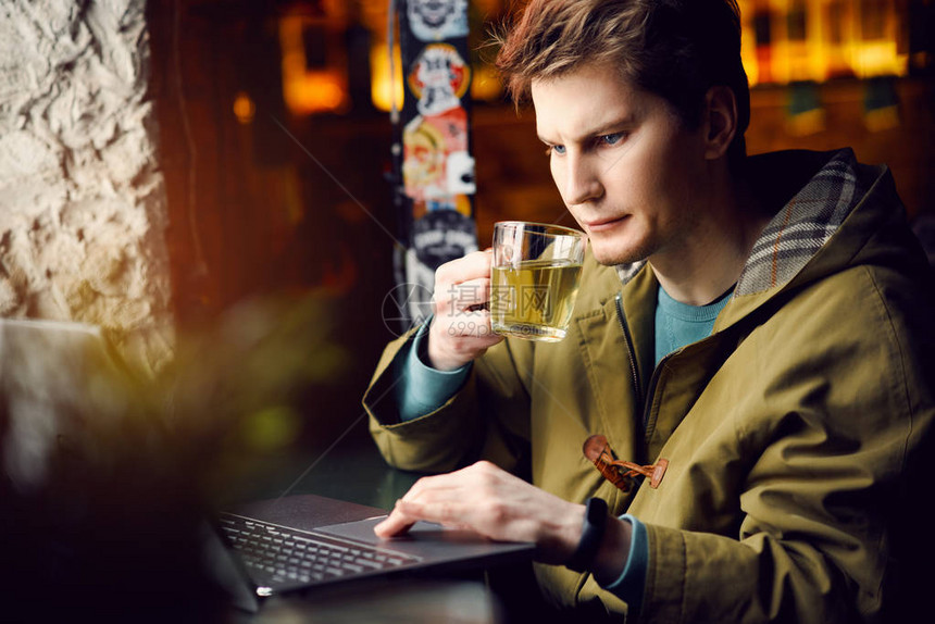 在咖啡馆工作的年轻人在电脑上工作和喝茶技术和生图片