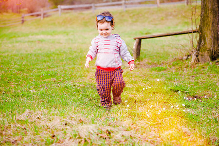 小太阳眼镜男孩在春草坪上行走图片
