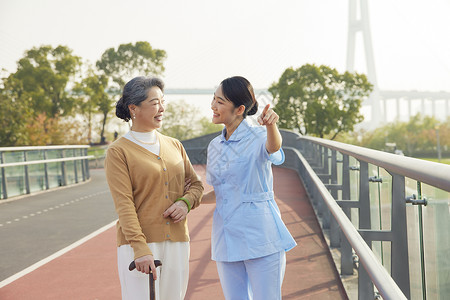 年轻女护工户外陪伴老人散步图片