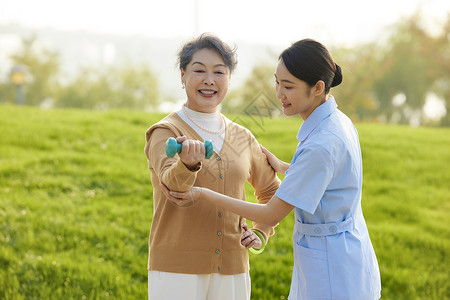年轻女护工指导老人康复运动高清图片