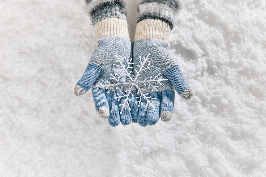 雪地里戴手套手捧雪花片特写图片