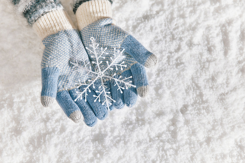 雪地里戴手套手捧雪花片特写图片