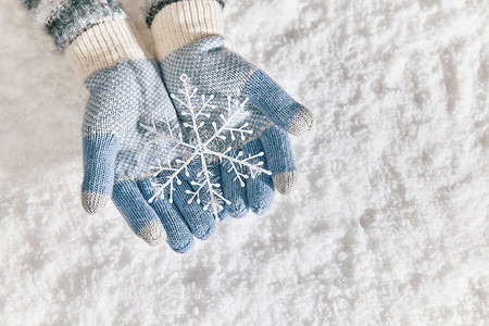 雪地里戴手套手捧雪花片特写背景图片