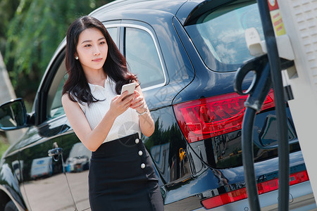 替代燃料使用青年女人使用手机自助充电汽车背景