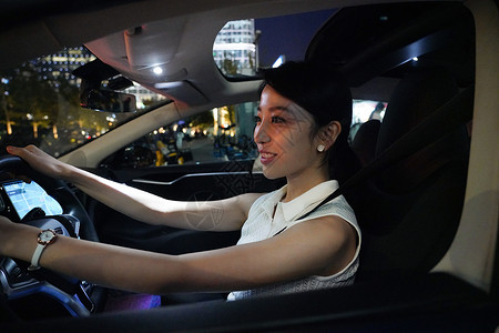 夜晚漂亮的青年女人驾驶汽车图片