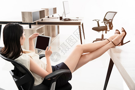 商务女士坐在椅子上用平板电脑高清图片