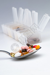 匙上的多色药丸和药盒背景图片
