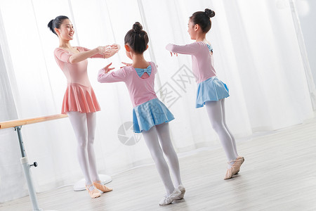 年轻舞蹈老师教小女孩们跳芭蕾高清图片