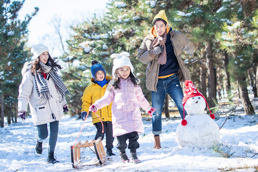 在雪地上玩雪橇的一家人图片