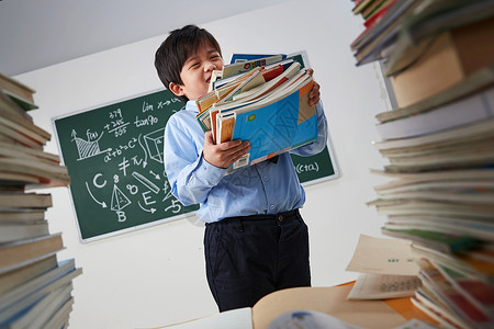 搬书搬着沉重课本的小学男生背景