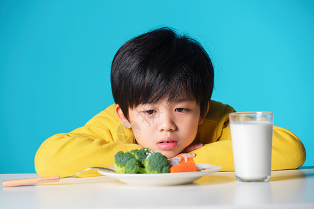 盯着蔬菜发愁的小男孩图片