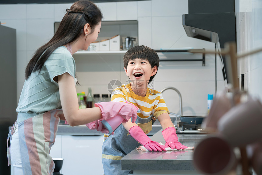 年轻妈妈指导儿子在厨房打扫卫生图片