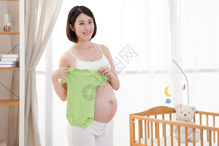 站着的宝宝孕妇拿着婴儿衣服背景