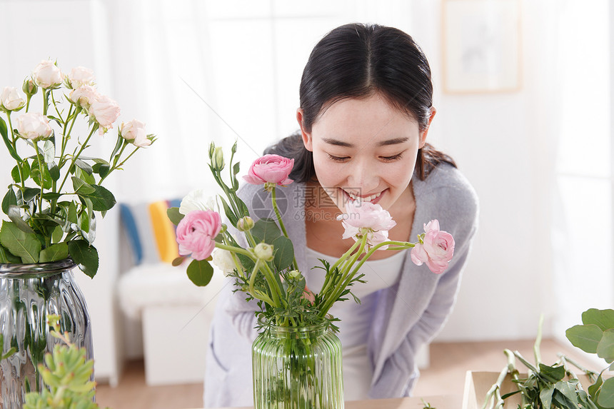 青年女人在闻鲜花的香味图片