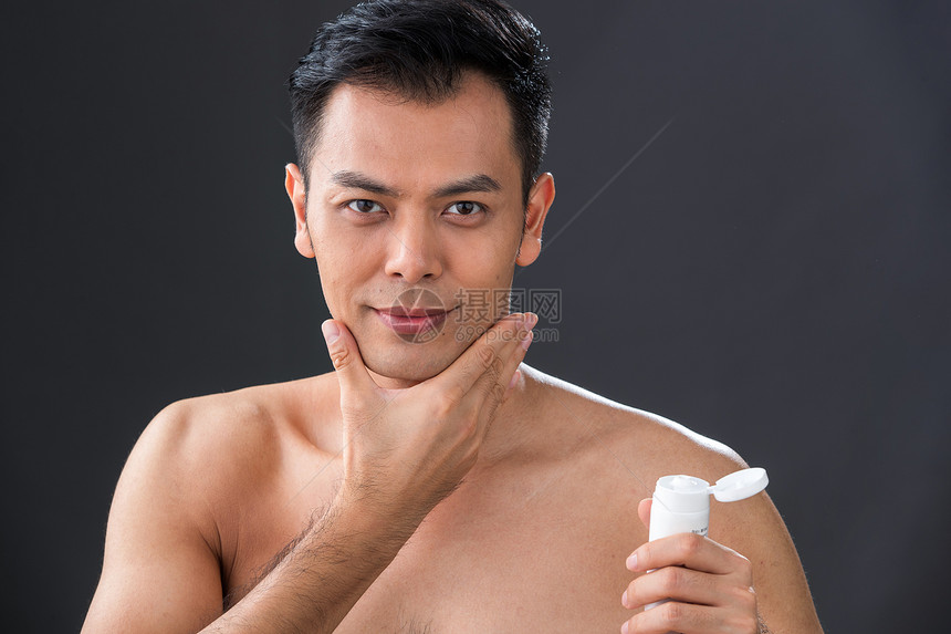 拿着剃须膏用手触摸下巴的男人图片