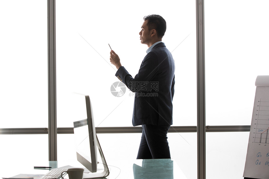 商务男士在窗户前看手机图片