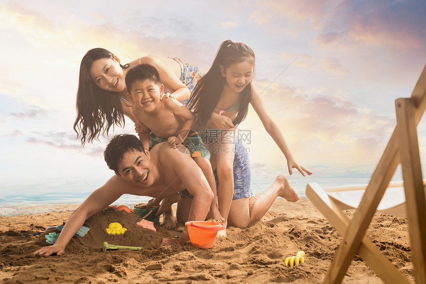 快乐的四口之家趴在沙滩上嬉戏图片