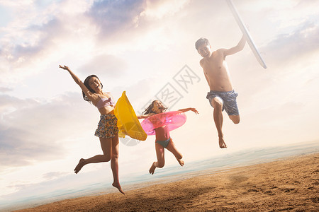 沙滩上跳跃的快乐三口之家高清图片