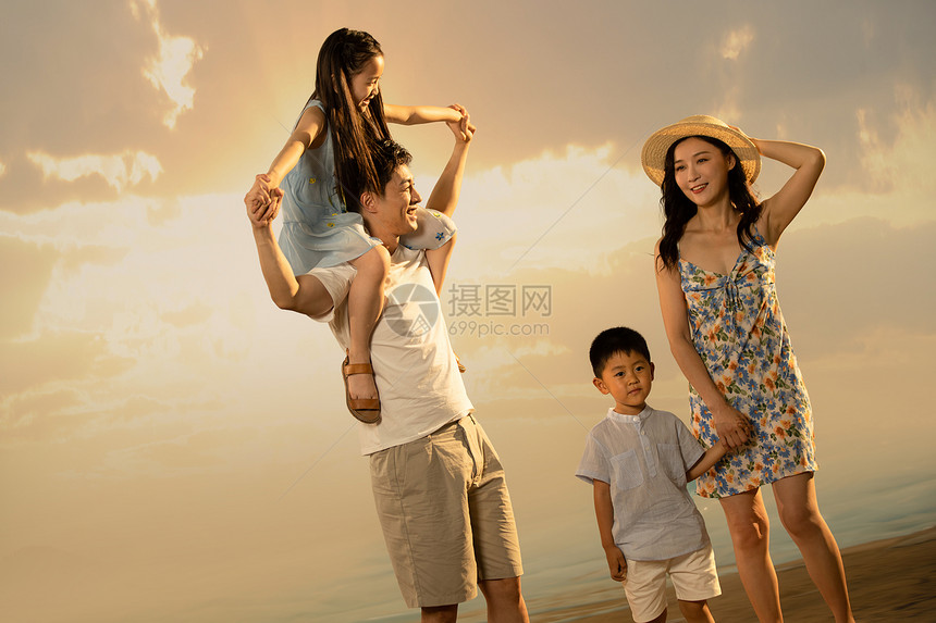 幸福的一家四口在沙滩上散步图片