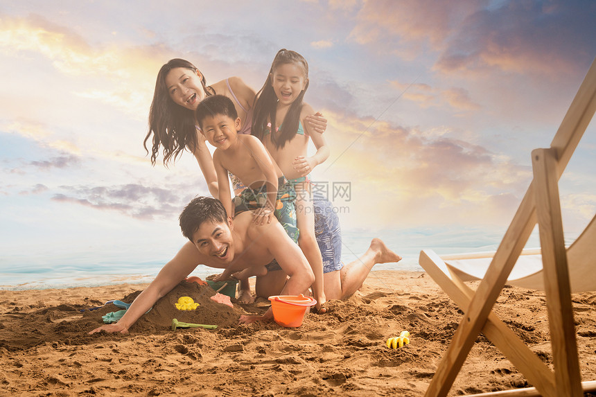 快乐的四口之家趴在沙滩上嬉戏图片