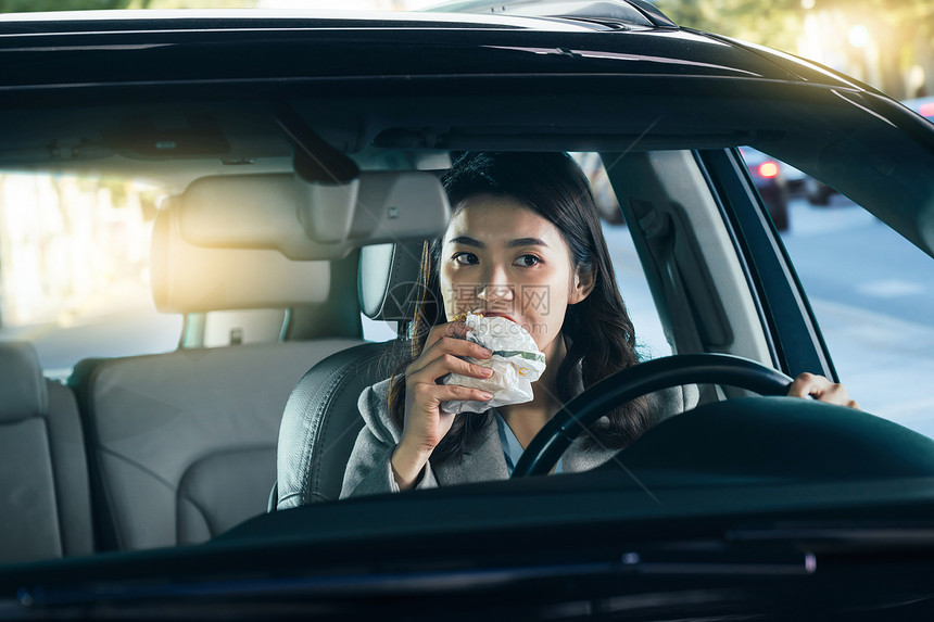 驾驶汽车的青年女人吃食物图片