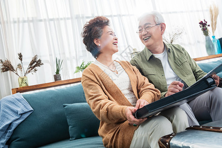 幸福的老两口坐在沙发上看相册背景图片