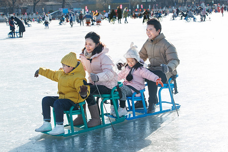 快乐的一家四口坐冰车玩耍高清图片