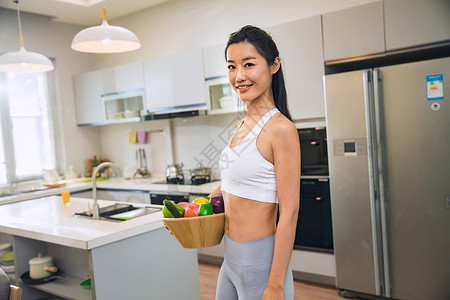 大家电穿着运动装的青年女人在厨房背景