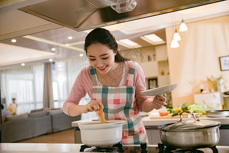 在锅里青年女人在厨房煲汤背景