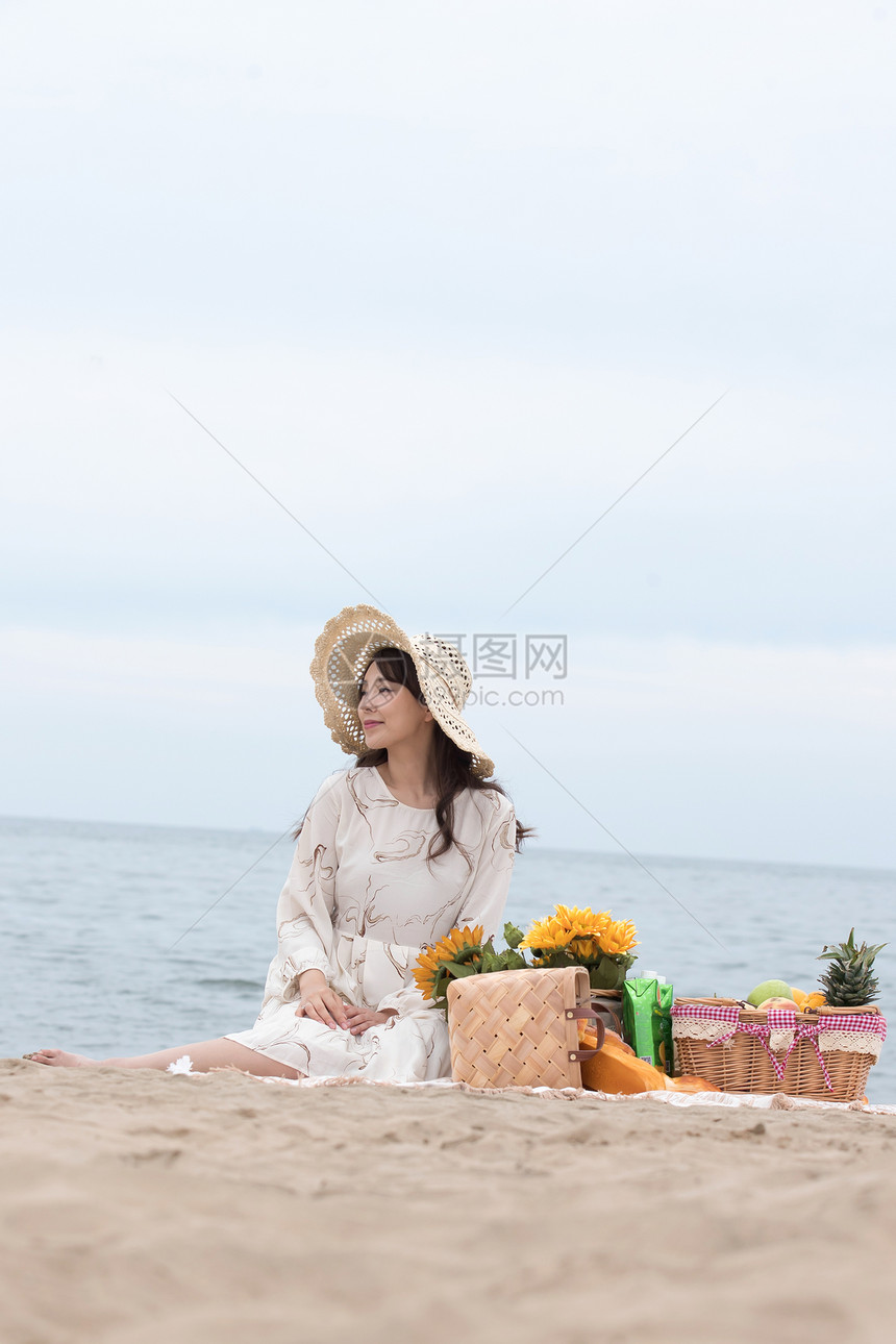 快乐的青年女人坐在沙滩上图片