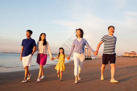 夕阳下在海边散步的幸福家庭图片