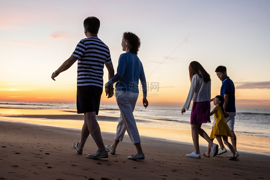 夕阳下在海边散步的幸福家庭图片