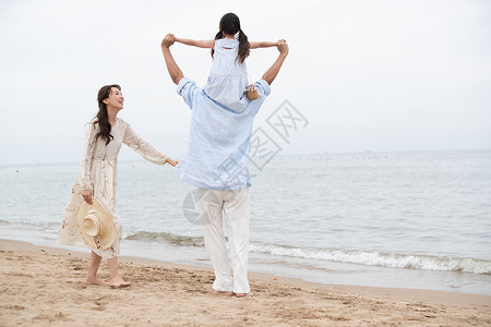 飞起来女孩幸福的一家三口在海边玩耍背景