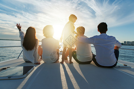 坐在船上弹琵琶的女孩夕阳下坐在游艇上的快乐一家人背景