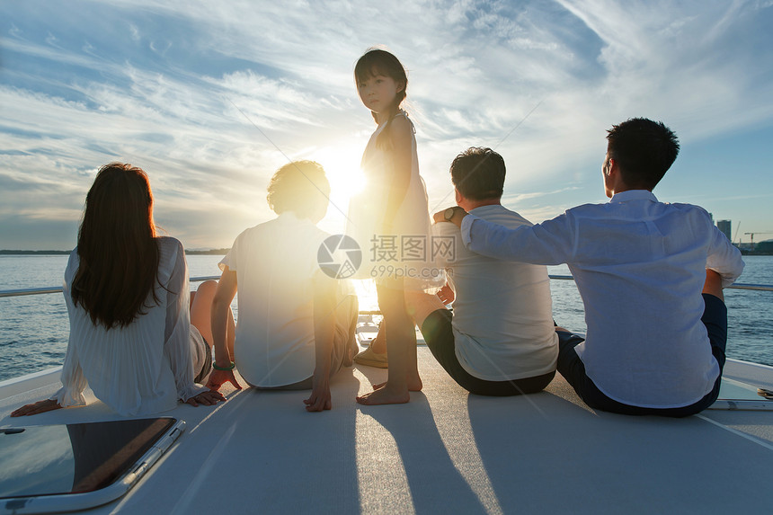 夕阳下坐在游艇上的快乐一家人图片