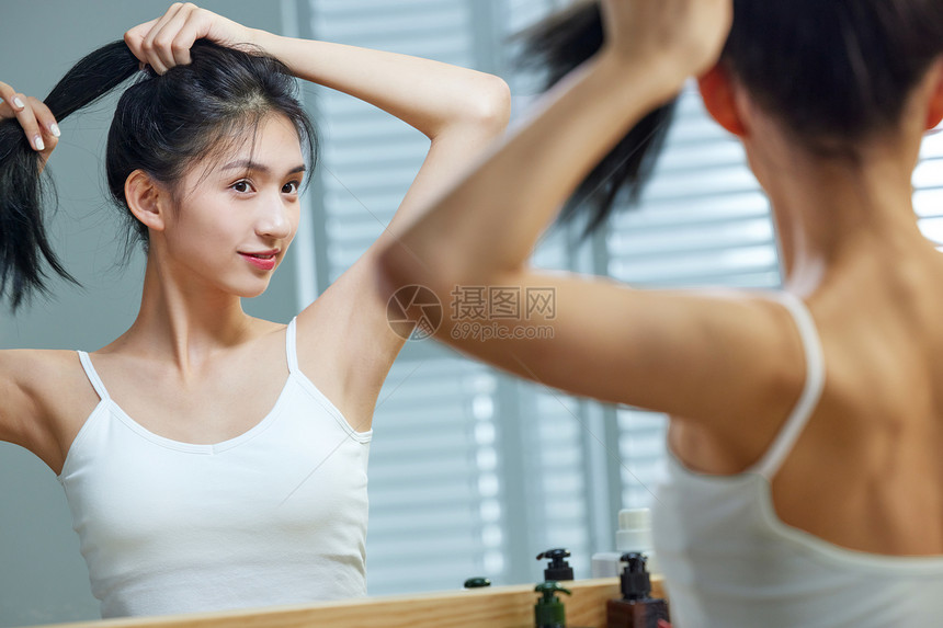 漂亮的年轻女人照着镜子梳头发图片