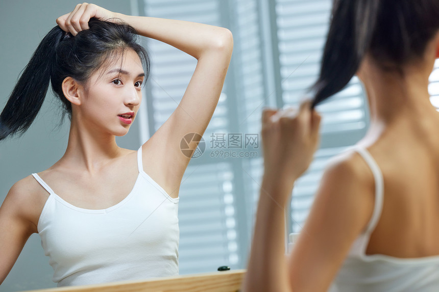 漂亮的年轻女人照着镜子梳头发图片