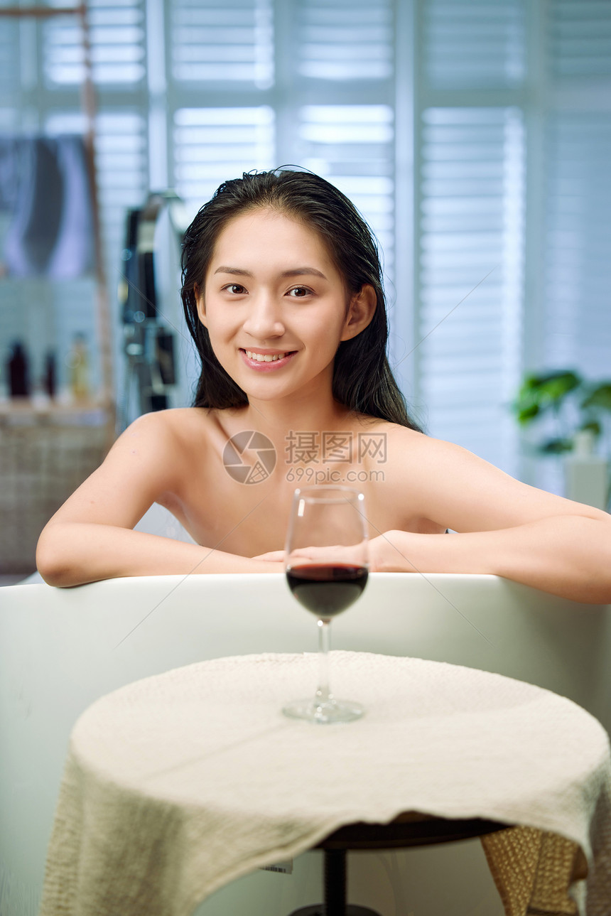 浴缸内漂亮的年轻女人和红酒图片