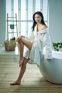身穿浴袍的青年女人坐在浴缸边图片