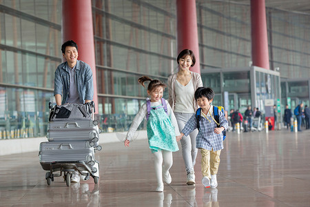 拖着行李的男孩欢乐家庭在机场推着行李背景